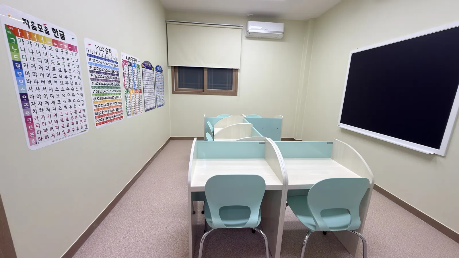 마주 보는 민트 의자와 흰 책상, 큰 칠판이 걸린 학습실